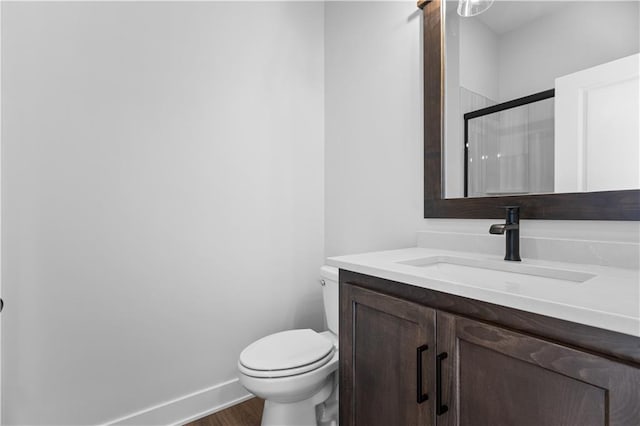 bathroom featuring vanity, hardwood / wood-style flooring, toilet, and a shower with shower door