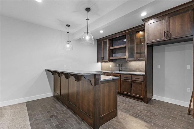 kitchen with dark brown cabinets, kitchen peninsula, a kitchen breakfast bar, and decorative light fixtures