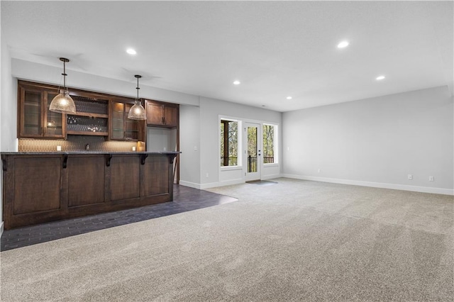 unfurnished living room featuring french doors, bar, and dark carpet