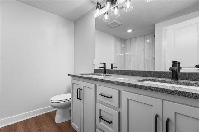 bathroom featuring toilet, hardwood / wood-style floors, a textured ceiling, vanity, and walk in shower