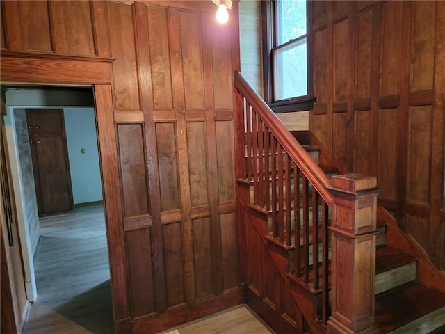 stairway with light hardwood / wood-style floors and wooden walls