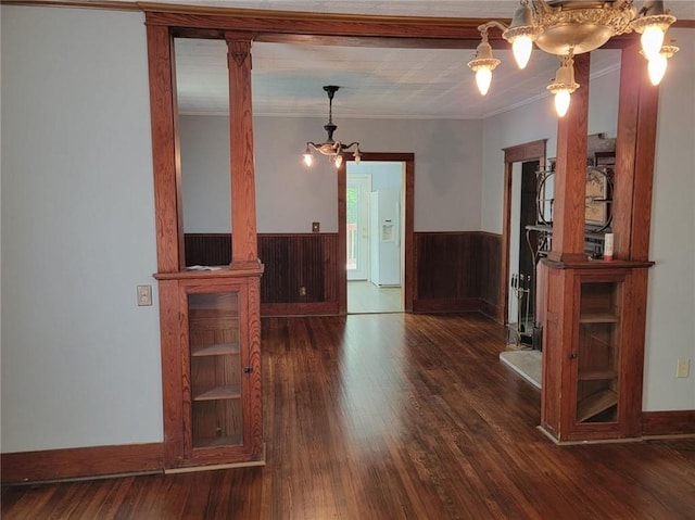 unfurnished room with a notable chandelier, dark wood-type flooring, and crown molding