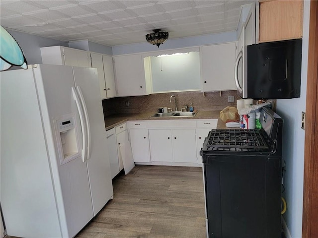 kitchen with backsplash, hardwood / wood-style floors, white cabinets, sink, and white appliances