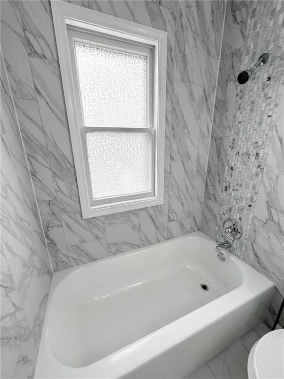 bathroom featuring a healthy amount of sunlight, marble finish floor, toilet, and shower / bathing tub combination