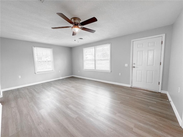 empty room with wood finished floors, a wealth of natural light, and baseboards