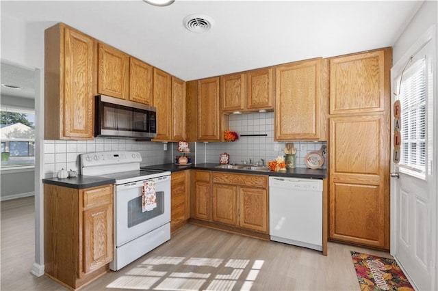 kitchen featuring dark countertops, white appliances, plenty of natural light, and visible vents