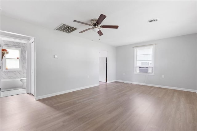 empty room featuring baseboards, visible vents, and wood finished floors