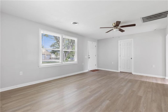 empty room with light wood-style floors, visible vents, ceiling fan, and baseboards