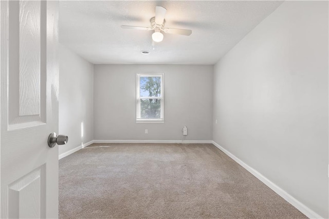 carpeted spare room with a textured ceiling, a ceiling fan, and baseboards