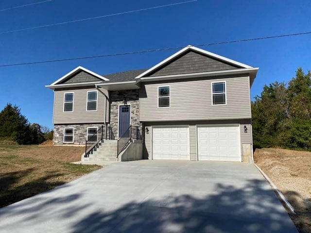 bi-level home featuring stone siding, concrete driveway, and an attached garage