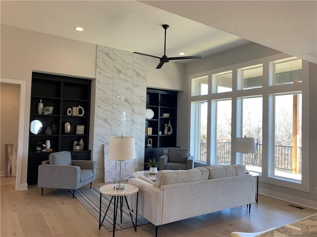 living room featuring hardwood / wood-style flooring, built in features, and ceiling fan