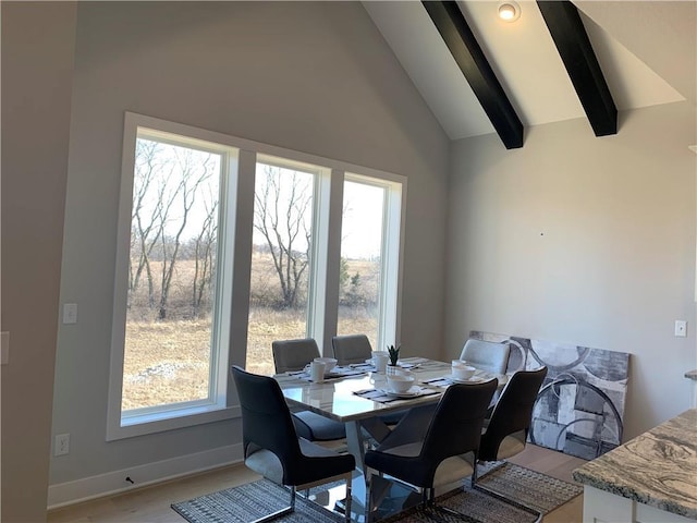 dining area with light hardwood / wood-style flooring, vaulted ceiling with beams, and plenty of natural light