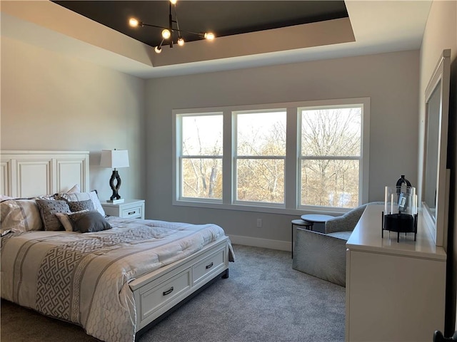 carpeted bedroom featuring a notable chandelier and a raised ceiling