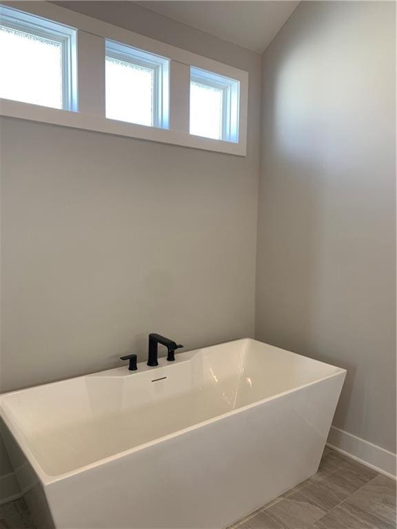 bathroom with vaulted ceiling and a bathtub