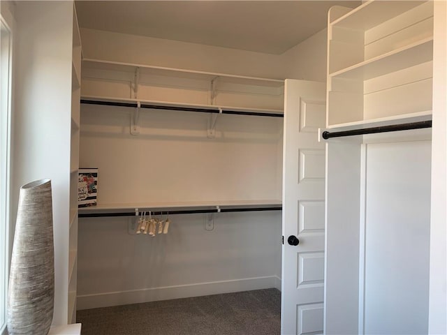 walk in closet with dark colored carpet