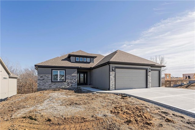 view of front of home featuring a shingled roof, stone siding, driveway, and an attached garage