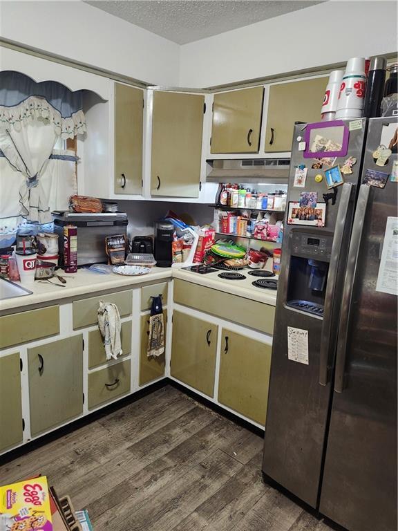 2821 Stark Ave, Kansas City, MO 64129 - kitchen featuring stainless steel fridge, light countertops, dark wood-style flooring, a textured ceiling, and under cabinet range hood