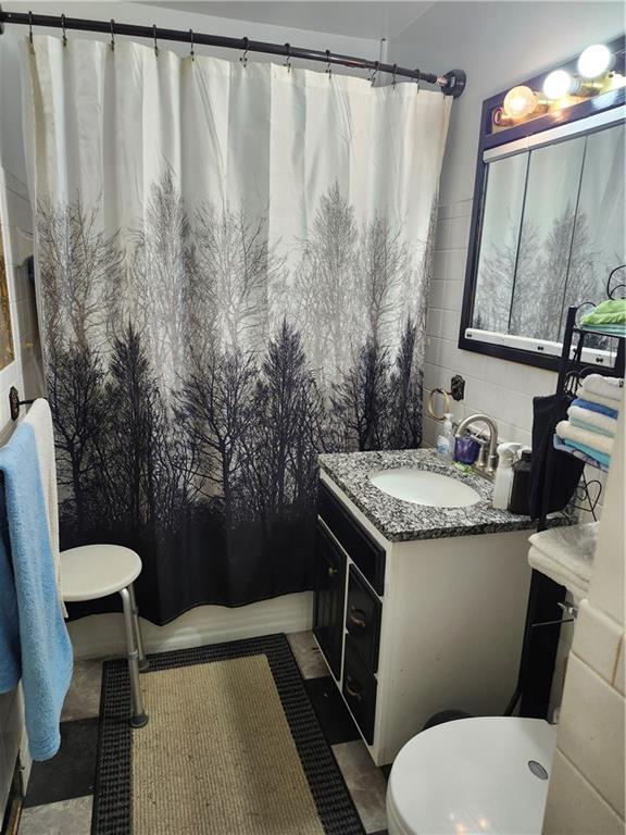 2821 Stark Ave, Kansas City, MO 64129 - full bathroom with vanity, a shower with curtain, and toilet