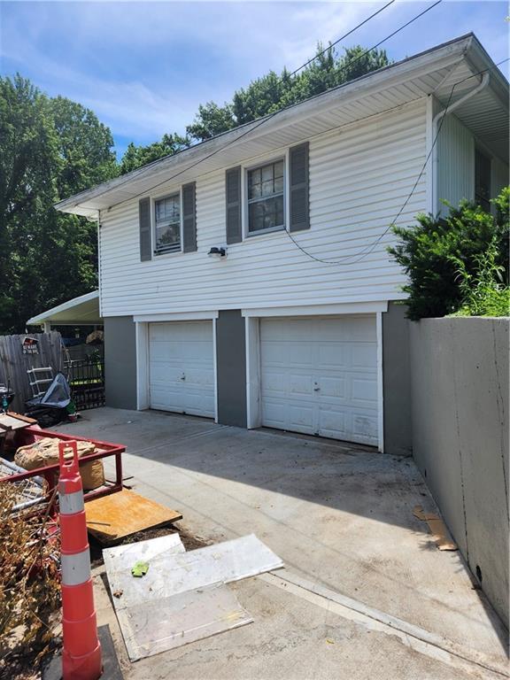 2821 Stark Ave, Kansas City, MO 64129 - view of front of home with fence, an attached garage, and driveway