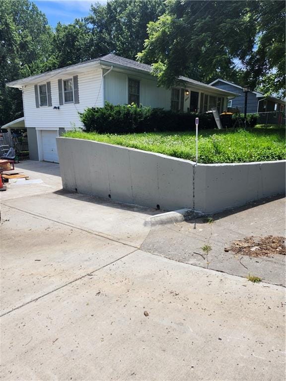 2821 Stark Ave, Kansas City, MO 64129 - view of front of property with an attached garage, concrete driveway, and fence