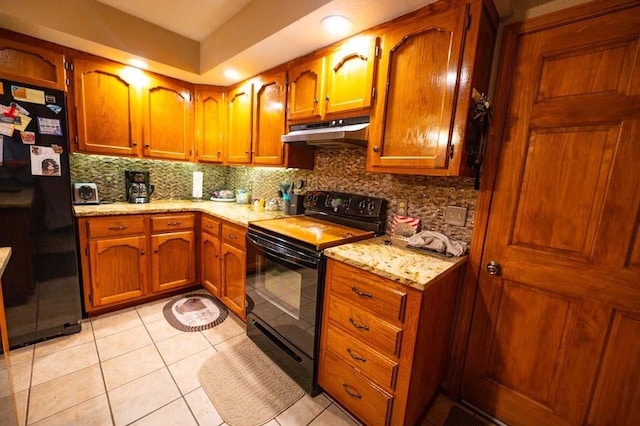 kitchen with backsplash, light stone counters, light tile patterned floors, and black appliances