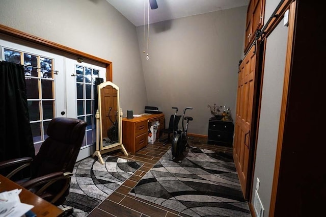 office area with a barn door, vaulted ceiling, and ceiling fan