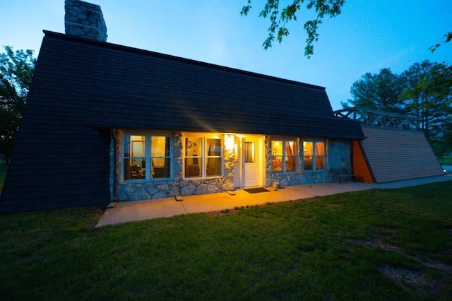 back house at dusk featuring a yard