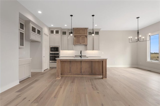 kitchen featuring light hardwood / wood-style flooring, a spacious island, appliances with stainless steel finishes, and decorative light fixtures