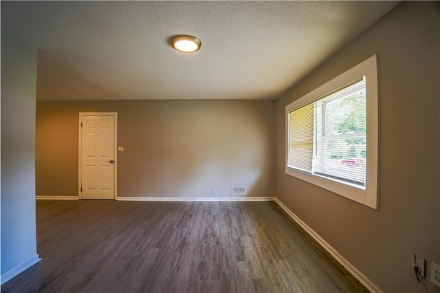 empty room featuring dark wood-type flooring and a textured ceiling