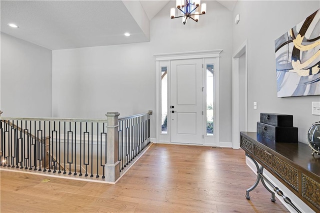 entryway featuring hardwood / wood-style flooring, an inviting chandelier, and lofted ceiling