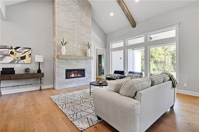 living room featuring beamed ceiling, light hardwood / wood-style floors, a fireplace, and high vaulted ceiling