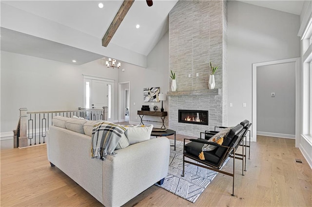 living room featuring high vaulted ceiling, light hardwood / wood-style flooring, a fireplace, beamed ceiling, and a notable chandelier