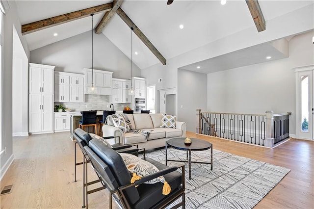 living room with beam ceiling, light hardwood / wood-style flooring, and high vaulted ceiling