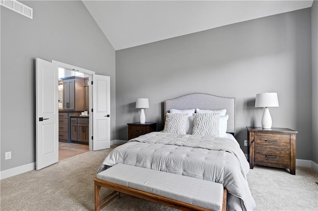 bedroom with light colored carpet, high vaulted ceiling, and ensuite bath