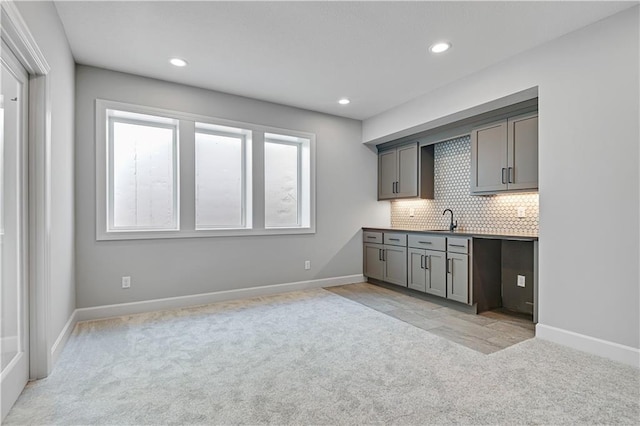 kitchen featuring tasteful backsplash, gray cabinets, light colored carpet, and sink