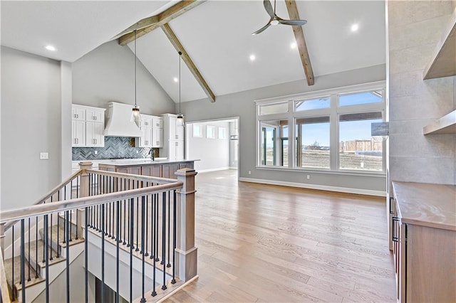 interior space featuring custom range hood, plenty of natural light, beamed ceiling, and tasteful backsplash