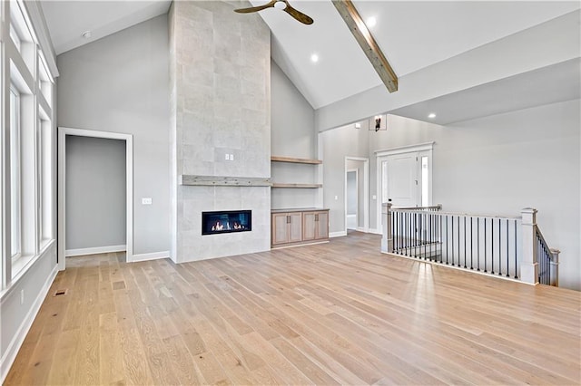 22047 W 94th St, Lenexa, KS 66220 - unfurnished living room featuring high vaulted ceiling, light wood-type flooring, ceiling fan, beamed ceiling, and a tiled fireplace