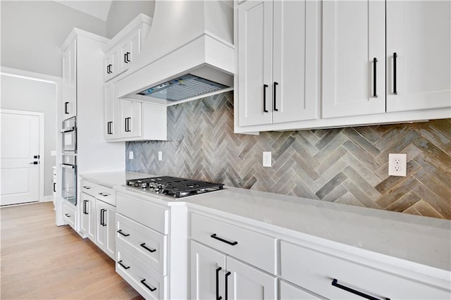 22047 W 94th St, Lenexa, KS 66220 - kitchen with custom range hood, stainless steel appliances, tasteful backsplash, white cabinets, and light wood-style flooring
