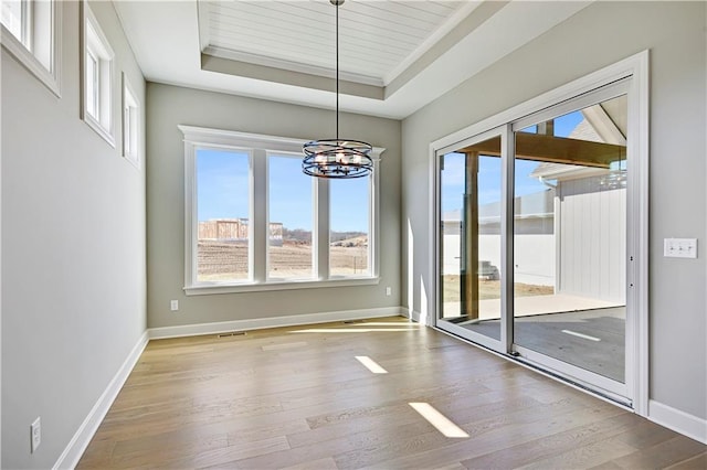 22047 W 94th St, Lenexa, KS 66220 - unfurnished dining area with a tray ceiling, wood finished floors, and a chandelier