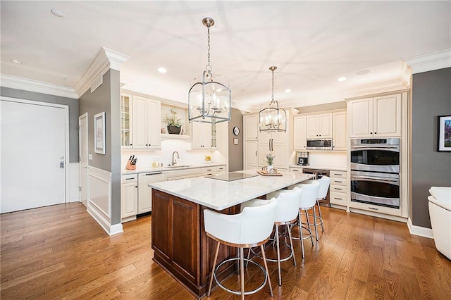 kitchen with a kitchen breakfast bar, a kitchen island, appliances with stainless steel finishes, hardwood / wood-style flooring, and pendant lighting