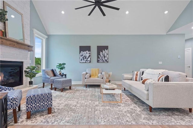 living room featuring vaulted ceiling, hardwood / wood-style flooring, a large fireplace, and ceiling fan