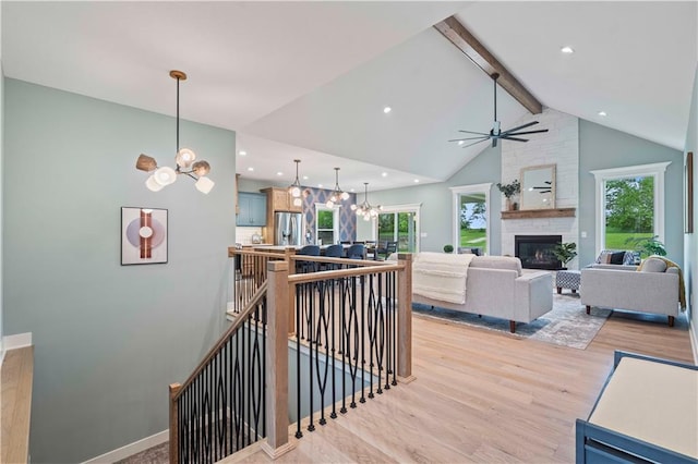 interior space featuring a large fireplace, beam ceiling, a wealth of natural light, and light wood-type flooring