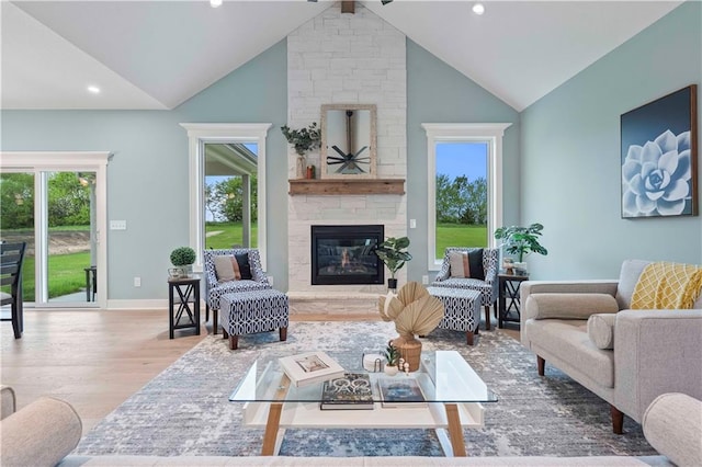 living room featuring high vaulted ceiling, a large fireplace, plenty of natural light, and light wood-type flooring