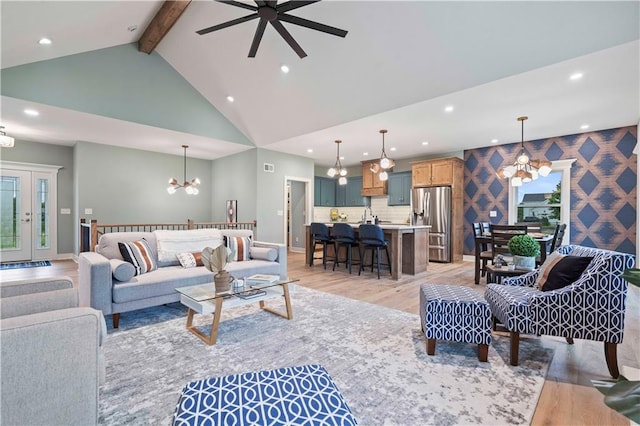 living room with ceiling fan with notable chandelier, light hardwood / wood-style flooring, high vaulted ceiling, and beamed ceiling