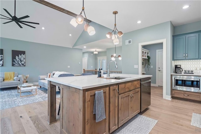 kitchen featuring lofted ceiling, a kitchen island with sink, pendant lighting, appliances with stainless steel finishes, and light hardwood / wood-style floors