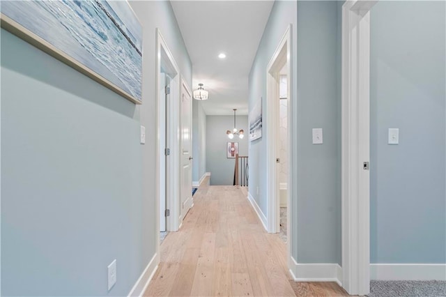 corridor with an inviting chandelier and light wood-type flooring