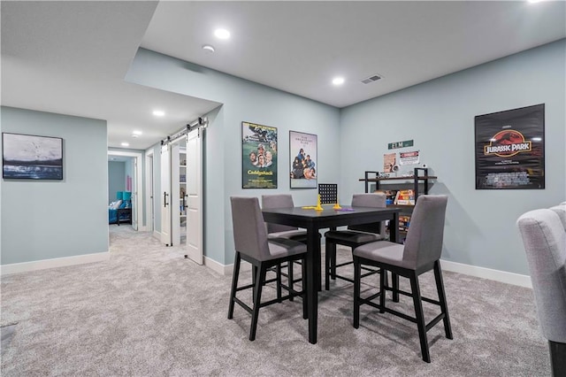 carpeted dining space with a barn door