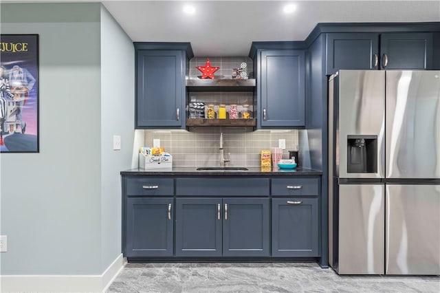 bar with stainless steel refrigerator with ice dispenser, sink, blue cabinetry, and decorative backsplash