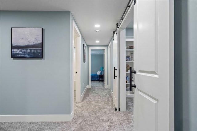 hallway with a barn door and light carpet