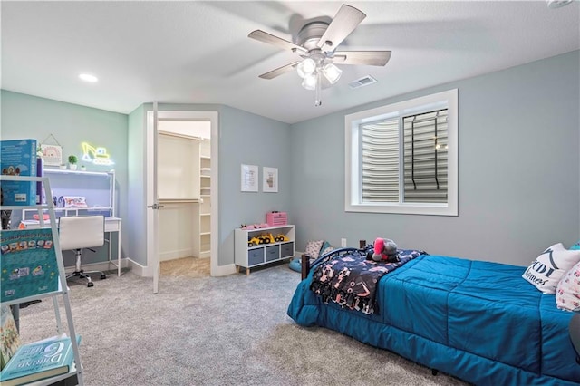 carpeted bedroom with a walk in closet and ceiling fan